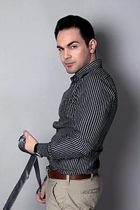 man in black and white pinstripe dress shirt holding black leather strap thumbnail
