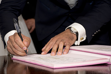 man with black blazer writing on white notebook close-up photography thumbnail