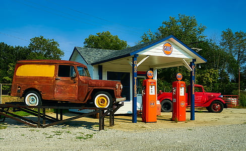 brown box truck on metal ramps beside gasoline station thumbnail