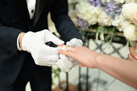 groom inserting wedding ring on brides finger thumbnail