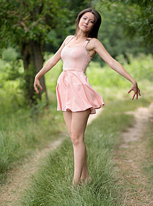 woman wearing pink sleeveless mini dress standing on green grass thumbnail