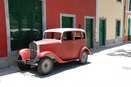 classic red vehicle parked on front of buildings thumbnail