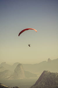 Person in Parachute Gliding Above Mountains thumbnail