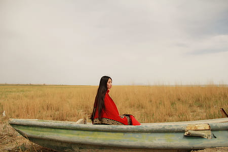 woman wearing red and brown cover sitting on boat thumbnail