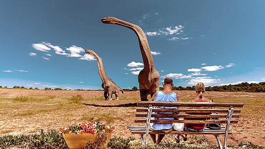 person sitting on brown bench with brontosaurus thumbnail