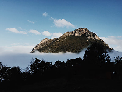 mountain peak over clouds under blue sky during daytime thumbnail