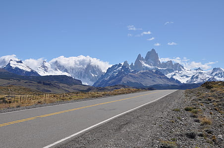 gray concrete road top near snow covered mountain at daytime thumbnail