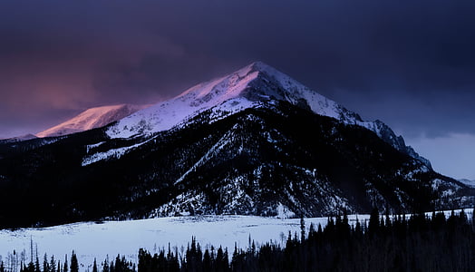 snow capped mountain under gray clouds at blue hour thumbnail