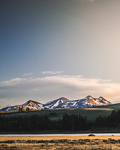 landscape photography of brown open field with snow-covered mountain background thumbnail