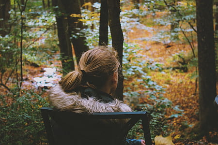 woman sitting on black chair near trees thumbnail