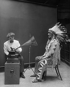 greyscale photo of native American sitting in front of gramophone thumbnail