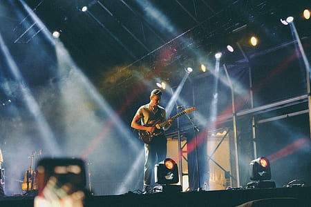 man carrying electric guitar standing on stage thumbnail