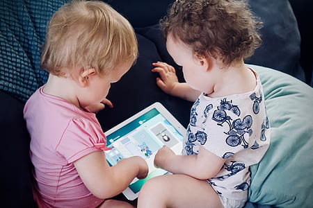 two babies watching Android tablet on blue sofa thumbnail