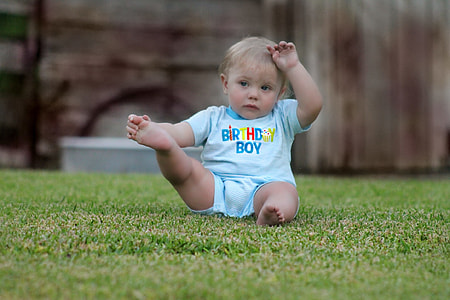 close up photography of boy sitting on grass field thumbnail