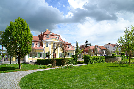 green grass field near houses under clouds thumbnail