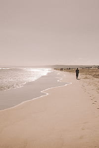 man standing at seashore with brown sand thumbnail