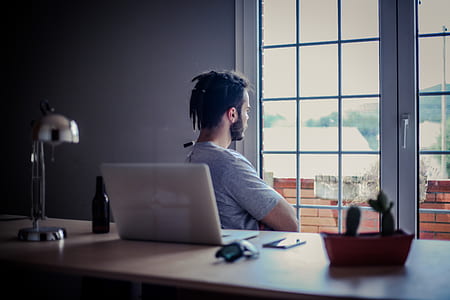man wearing grey shirt sitting on chair front of window thumbnail
