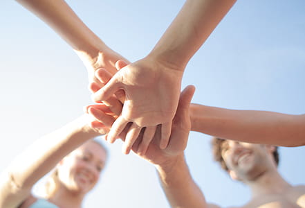A group of people in a huddle outdoors on a summer day thumbnail