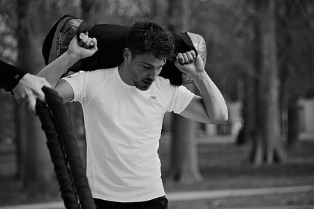 grayscale photography of man carrying duffel bag thumbnail