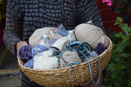 person holding brown and purple yarns in basket thumbnail
