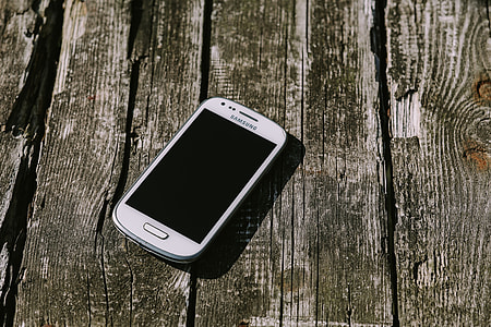 White smartphone with various items on a wooden background thumbnail