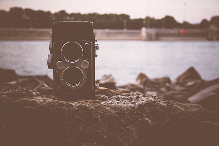 vintage black camera on rock with body of water in distance thumbnail