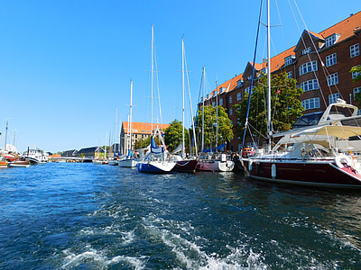 sailing yachts across tall houses under blue sky thumbnail