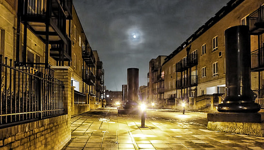 turned-on bollard lamp between concrete buildings thumbnail