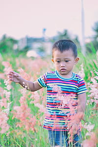 Boy Walking on Bush-covered Field Selective Focus Photo thumbnail