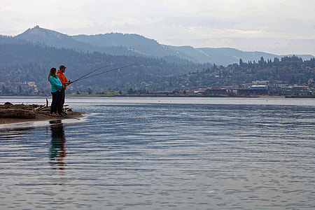 man and woman fishing near edge of water thumbnail