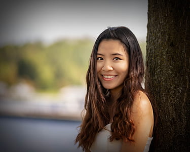 smiling woman leaning against tree thumbnail