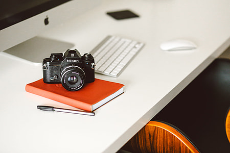 black Nikon DSLR camera on top of orange book thumbnail