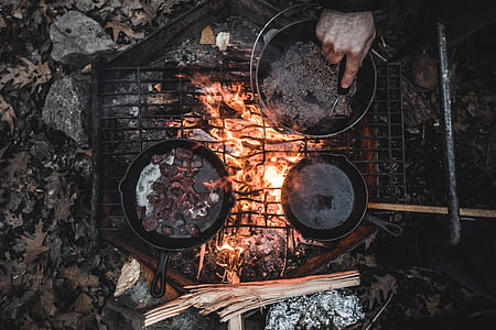 man cooking on grill using cooking pad and skillet at daytime thumbnail