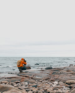 person sitting near body of water while taking a photo thumbnail
