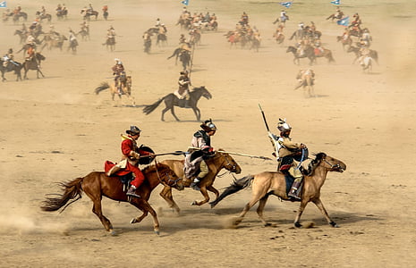 group of people riding horses in sandy area thumbnail
