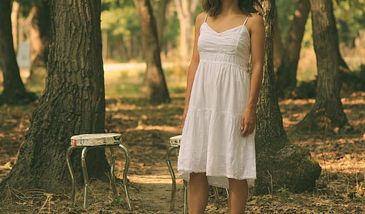 woman standing beside white stool in white spaghetti strap dress thumbnail
