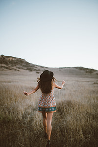 woman in brown and green dress walks on brown grass field thumbnail
