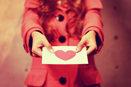 woman holding white and pink printer paper thumbnail