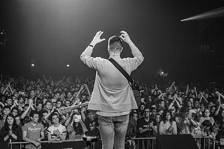man on stage in front of group of people grayscale photography thumbnail