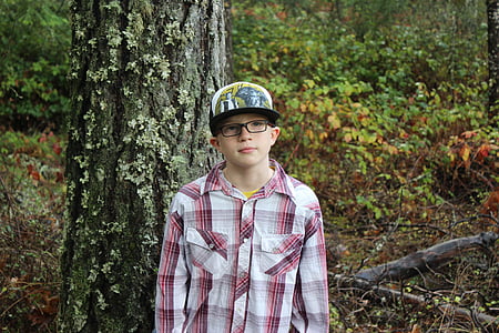 boy standing near gray tree trunk thumbnail