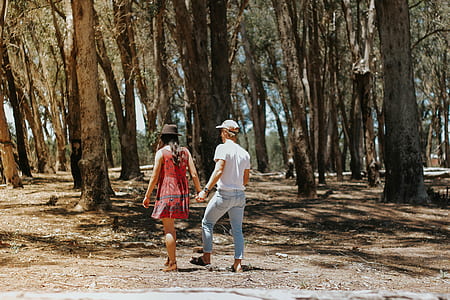 woman and man standing while walking near trees during daytime thumbnail