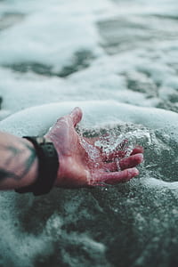 person's hand touching body of water thumbnail