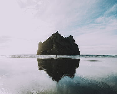 landscape photo of rock formation surrounded by body of water thumbnail