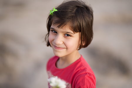 focus photo of girl in red and white crew-neck top wearing green hair pin thumbnail