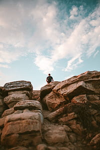 man standing on brown rock mountain thumbnail