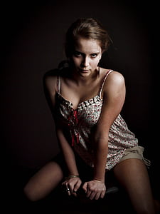 woman wearing white, red, and green floral spaghetti strap mini dress sitting on chair holding seat pad with her pair of hands thumbnail