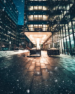 falling snow on glass building during nighttime thumbnail