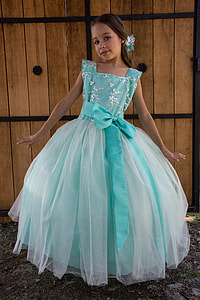 girl in teal tulle dress standing near brown wood door thumbnail