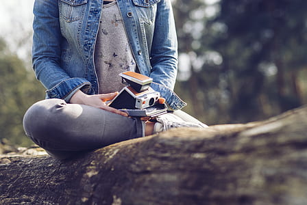 selective focus photography of woman sitting on tree trunk thumbnail