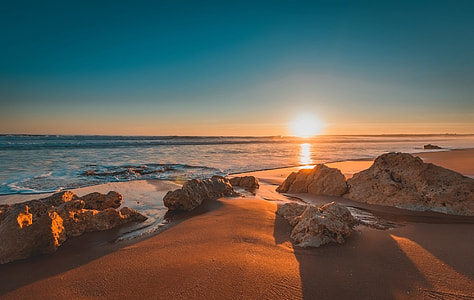 brown rock near body of water during sunset thumbnail